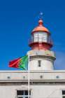 Ponta Delgada, Azores, Portugal. Portuguese flag and Albarnaz Lighthouse on Flores Island. Art Print
